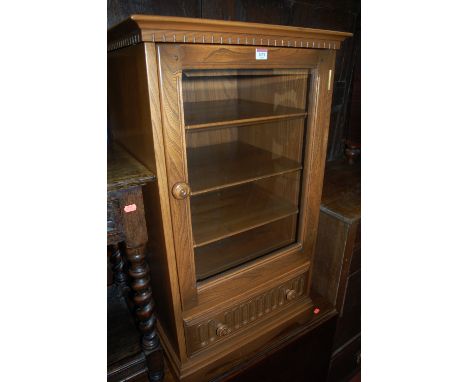 An Ercol mid elm single door glazed hi-fi cabinet having single long lower drawer