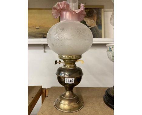 A brass oil lamp with frosted shade