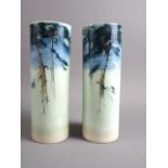 A pair of Royal Worcester "Sabrina Porcelain" cylinder vases, decorated pine trees at night,