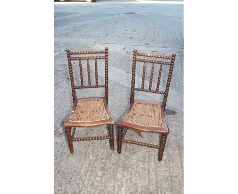 A pair of bobbin turned chairs with cane seats and spindle back 