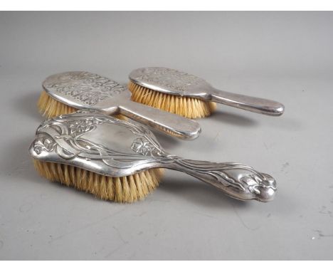 An Arts &amp; Crafts style silver backed hair brush, by Liberty &amp; Co, a matching hair brush, by W H Hasseler, and an Art 