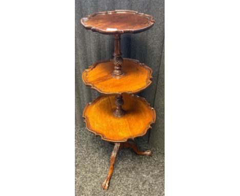 A reproduction three tier mahogany dumb-waiter with pie crust edging raised on tripod base ending in claw and ball feet. [102
