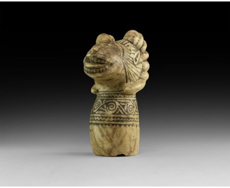 An undated archaistic carved stone finial with barrel-shaped socket and band of spiral tendril between zigzags, stylised ram'