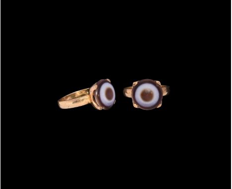 19th-20th century AD. A gilt finger ring with C-section hoop, discoid bezel with flange and inset banded agate bead as a cabo