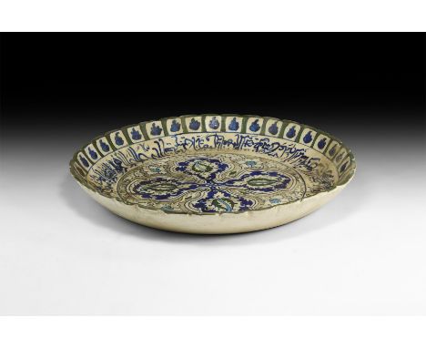 An undated archaistic glazed ceramic charger with dentilled rim, band of calligraphic text and large central quatrefoil with 