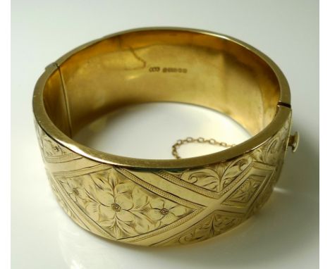 A 9ct gold hinged cuff bangle, the body engraved with scrolls and floral panels within diamond shaped borders, complete with 
