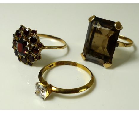 A collection of three dress rings, comprising a 9ct gold and smokey quartz dress ring, the emerald cut stone 22 by 16mm, size