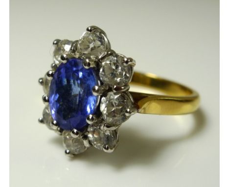 An 18ct gold, tanzanite and diamond flowerhead ring, the central oval cut tanzanite of approximately 9 by 6.8mm and surrounde