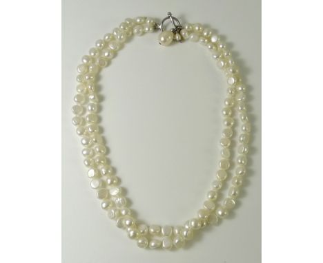 A double string of irregular button shaped pearls, with silver T bar and circle clasp to a single baroque pearl drop, pearls 