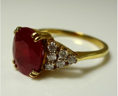 An 18ct gold, carnelian and diamond dress ring, the central oval cut carnelian of approximately 10.4 by 8.5 by 5.7mm, flanked