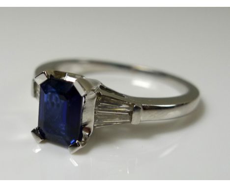 An 18ct white gold sapphire and diamond ring, the central emerald cut royal blue sapphire approx 0.92ct, flanked by two pairs