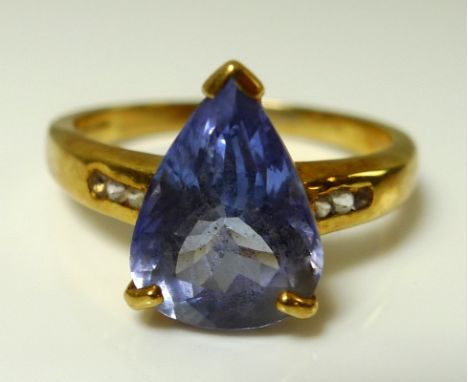 An 18ct gold and tanzanite ring, the central pear cut tanzanite of approximately 12.1 by 8.8 by 5.9mm, set with three white s