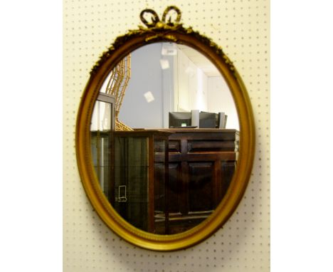 An oval gilt framed mirror, ribbon tied
