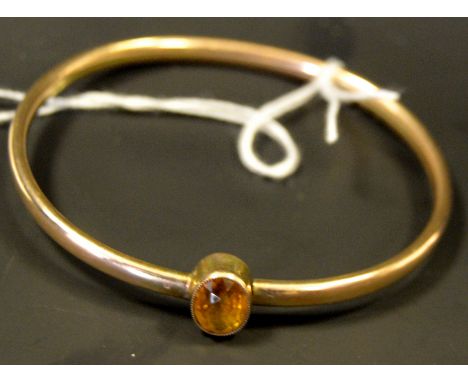 A gold coloured metal bangle, set with a citrine stone, 9.2g gross