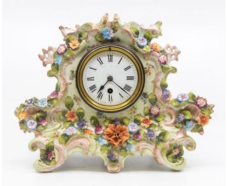 An early Edwardian single train mantle clock in a porcelain case decorated with flowers, key and pendulum present