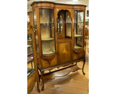 An Edwardian mahogany glass display cabinet, having an open central shelf with bevelled mirror, two bow-fronted glass side se