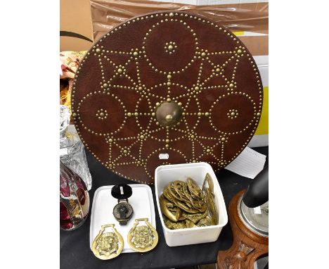 A collectors lot to include a replica shield, leather with brass and tartan detailing, with a collection of horse brasses and