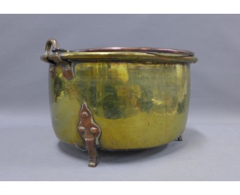 Arts &amp; Crafts copper and brass pan / planter, with a swing handle and raised on three feet, 44cm wide