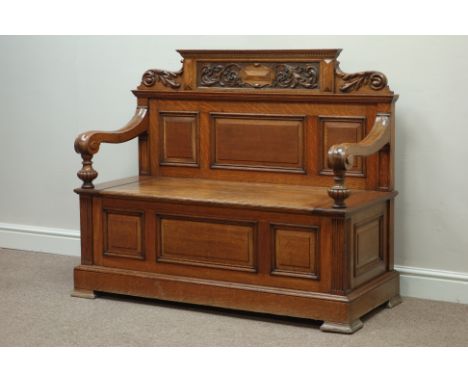 Edwardian golden oak hall bench with fielded panels, the back with leaf carved dentil cresting, hinged seat, down curved arms