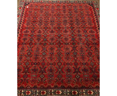 Hamadan red ground rug carpet field repeating geometric motifs within a chevron and stylized floral border, 295cm x 280cm   C