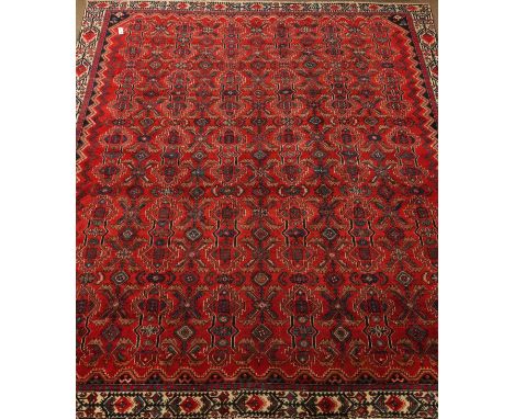 Hamadan red ground rug carpet field repeating geometric motifs within a chevron and stylized floral border, 295cm x 280cm   C