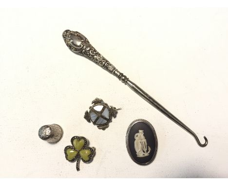 A silver thimble, a silver button hook, a Wedgwood cameo, a silver three leaf clover, and another brooch.