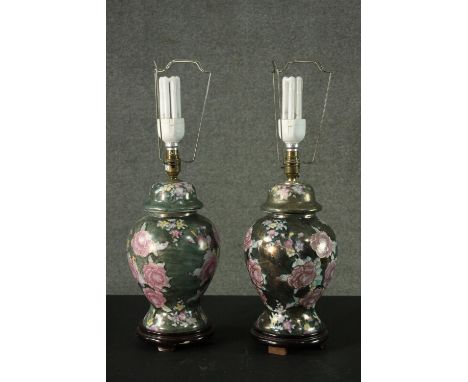 A pair of Oriental style rose design ceramic lustre urn vases converted to table lamps. Each sitting on a hardwood base. H.54