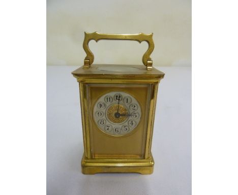A brass carriage clock with silvered dial, Arabic numerals and swing handle