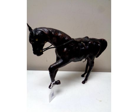 A vintage leather horse figure with foot raised, height 26 cm.