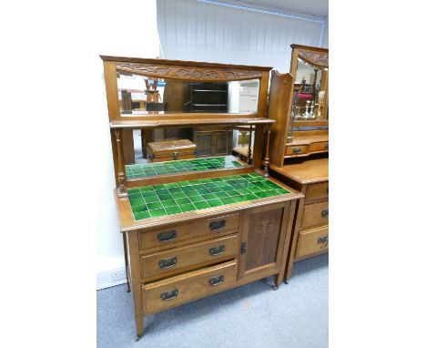 An Art Nouveau mirror backed side board with a three drawer and single door base with Marquetry inlay below a green tiled top