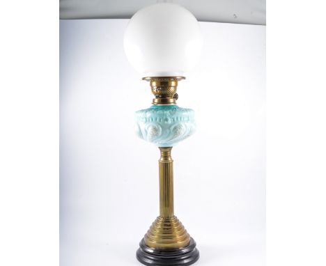 A Victorian brass oil lamp, fluted column, moulde and opaque reservoir, complete with chimney and shade, 74cm overall.