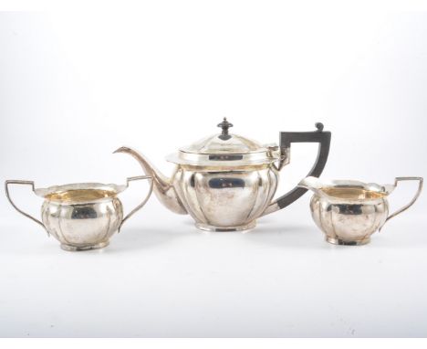 A white metal three-piece teaset, marked SILVER 90S, comprising a lightly fluted oval teapot with composition handle and fini
