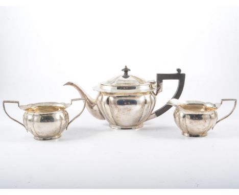 A white metal three-piece teaset, marked SILVER 90S, comprising a lightly fluted oval teapot with composition handle and fini