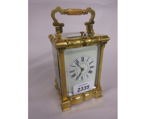Small late 19th or early 20th Century gilt brass cased carriage clock, the serpentine shaped case enclosing an enamel dial wi
