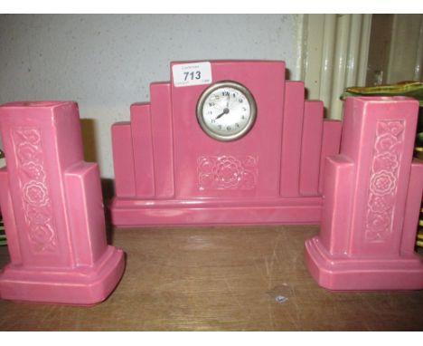 Sarreguemines Art Deco mantel clock, decorated with a pink glaze together with a pair of matching side urns