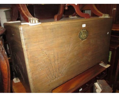 20th Century oriental carved camphor wood trunk with hinged lid together with an oriental silk work firescreen in an ebonised