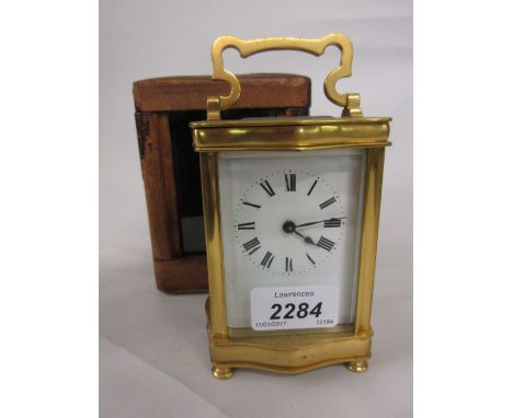 Early 20th Century gilt brass carriage clock, the serpentine shaped case enclosing an enamel dial with Roman numerals and sin