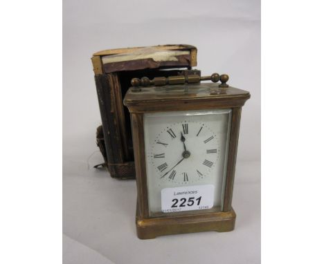 Small brass cased carriage clock with enamel dial and Roman numerals and a single train movement (a/f) in a leather box