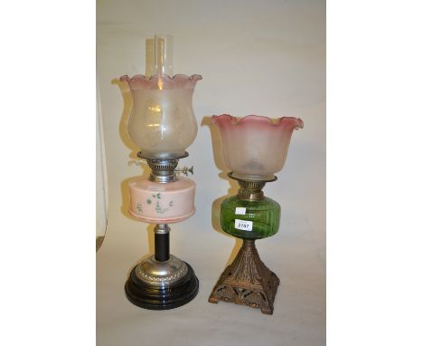 Victorian cast iron and green glass oil lamp with etched shade together with a similar oil lamp with pink well and etched sha