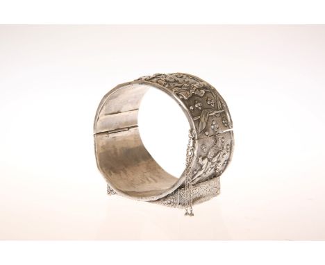 A CHINESE SILVER BANGLE, late 19th or early 20th Century, chased with figures and flowerheads, the reverse with inset hammere