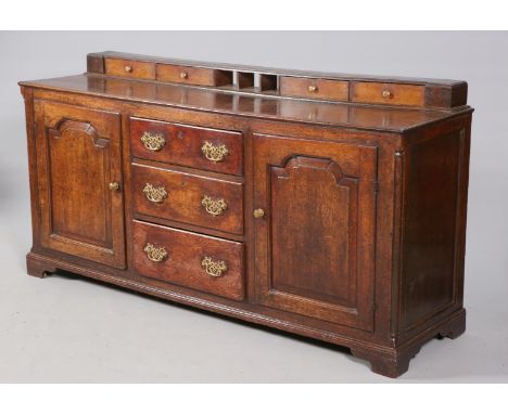 A GEORGE III OAK DRESSER BASE, the moulded rectangular top with spice drawers, over three drawers with pierced brass backplat