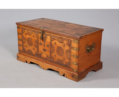 A 19TH CENTURY BRASS STUDDED TEAK TRUNK, the studs arranged in a geometric formation, with brass carrying handles. 50.5cm by 