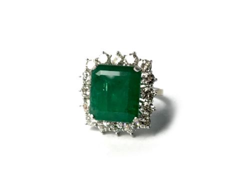 IMPRESSIVE GREEN GEM SET AND DIAMOND RING, the step cut gem 14.8x13.2mm, surrounded by a halo of round brilliant cut stones t