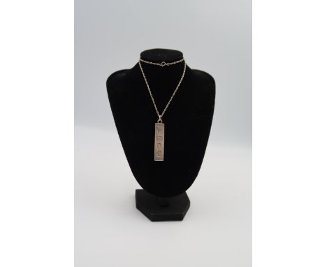 A silver ingot pendant on chain, circular silver pendant and a pewter pipe tamper