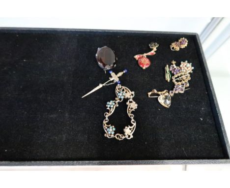 An assortment of items to include: a white metal oval smokey quartz brooch; a bow brooch suspending a heart shape citrine, st