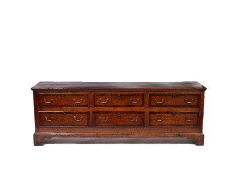 A GEORGE III OAK LONG LOW DRESSER BASE with mahogany cross banded top and further cross banding to the drawer front and panel