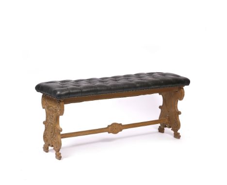 A BLACK BUTTON UPHOLSTERED LEATHER WINDOW SEAT standing on carved classical style supports, united by a stretcher, 143cm x 61