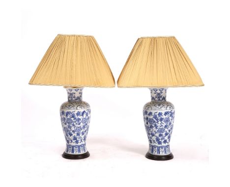 A PAIR OF BLUE AND WHITE PORCELAIN TABLE LAMPS of baluster form with square pleated silk shade, the base 37.5cm high, the lam