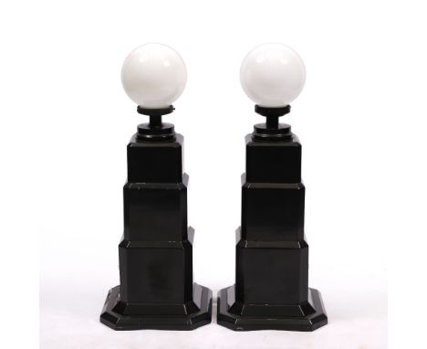 A PAIR OF ART DECO EBONISED LAMP STANDS  with white glass spheres on the stepped bases, each 34cm wide x 86cm high