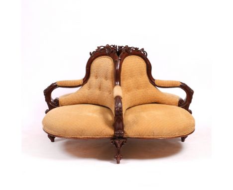 A VICTORIAN STYLE BUTTON UPHOLSTERED CONVERSATION SEAT with four carved scrolling arms and four scrolling legs, 148cm wide 